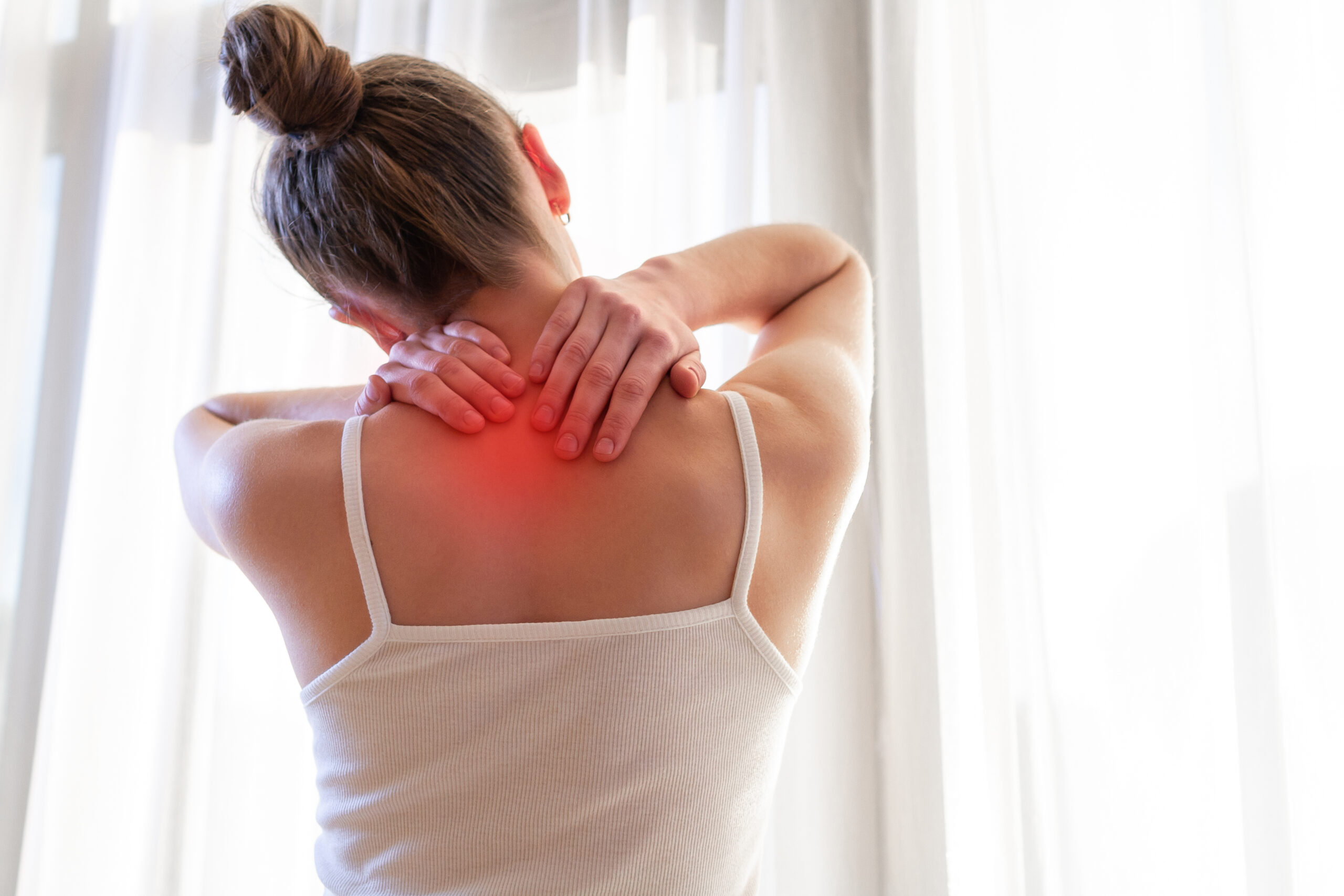 woman with chronic pain rubbing her neck after the pain flared up in her lower neck/upper back region